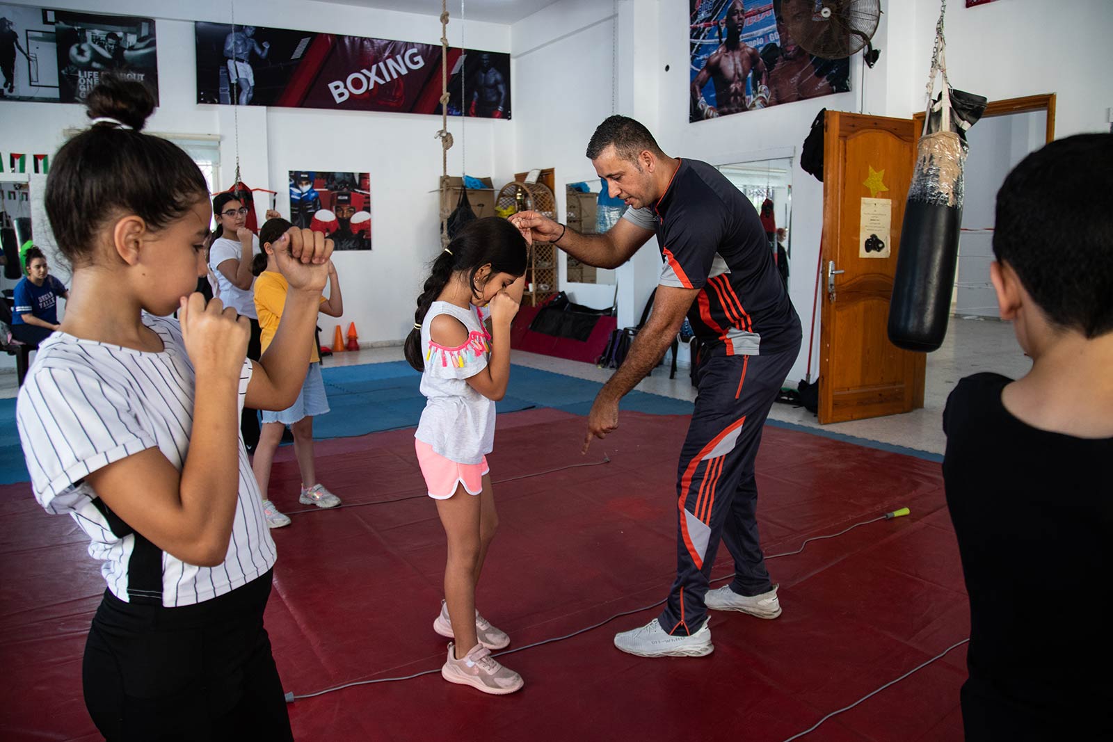 A teacher points to the feet of his student, making sure her stance is correct