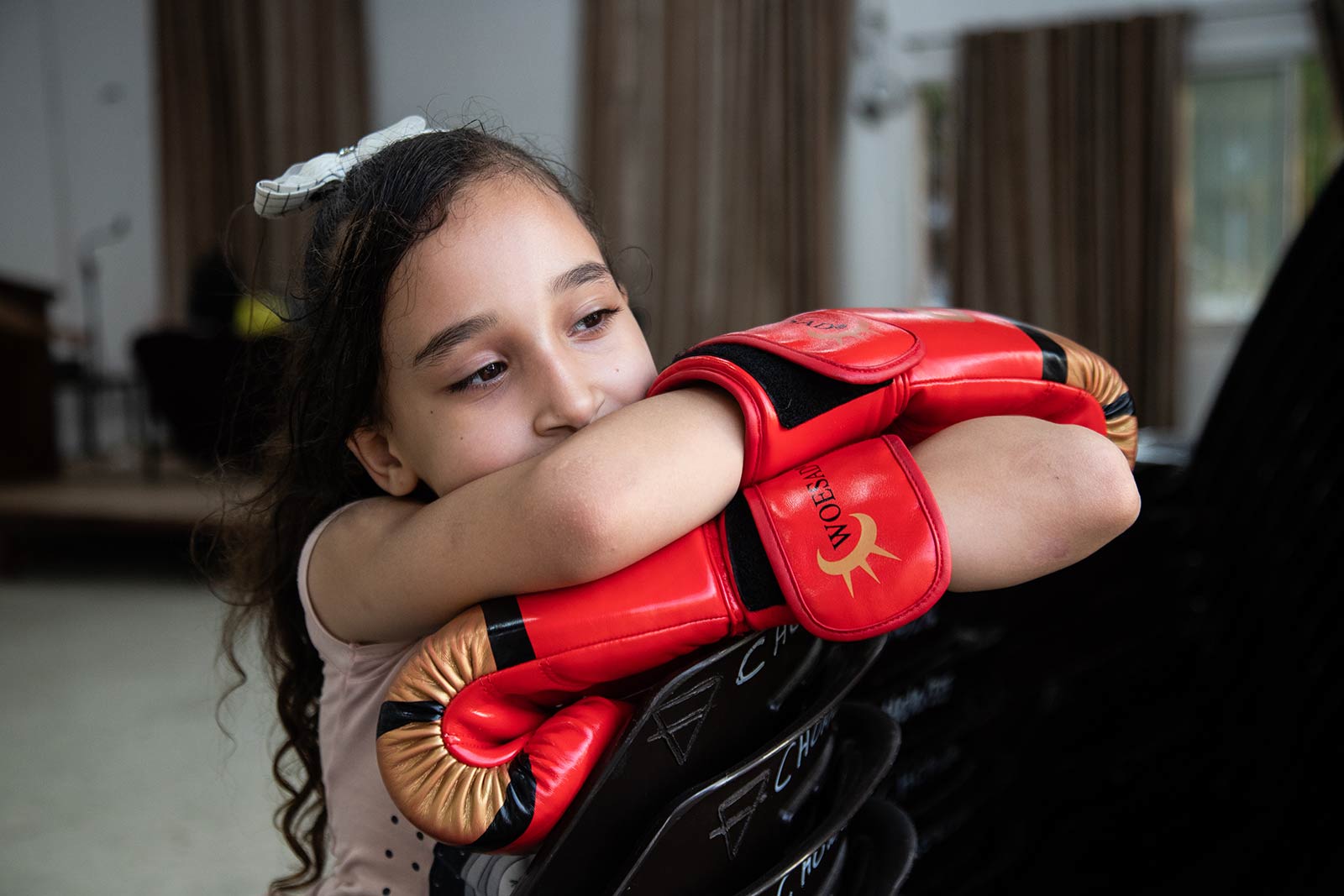 A young girl, leans relaxing on her arms, with boxing gloves