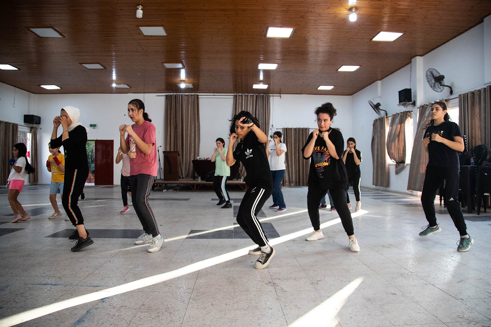 A row of girls & young women practice their boxing stances