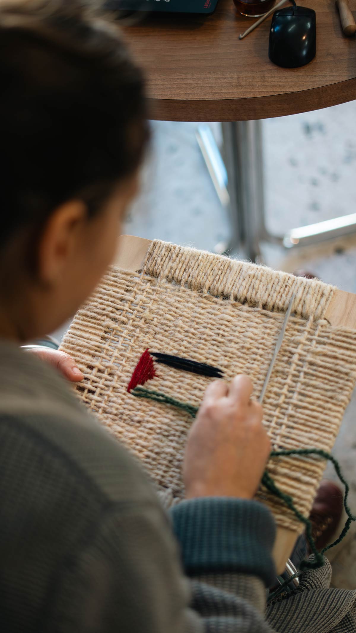 Lara embroidering the Palestinian flag with wool on a woven frame.